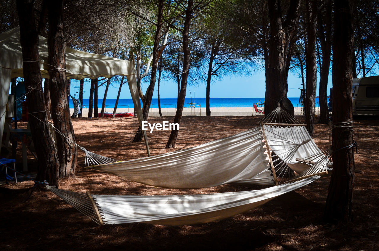 Hammocks hanging at beach against sky