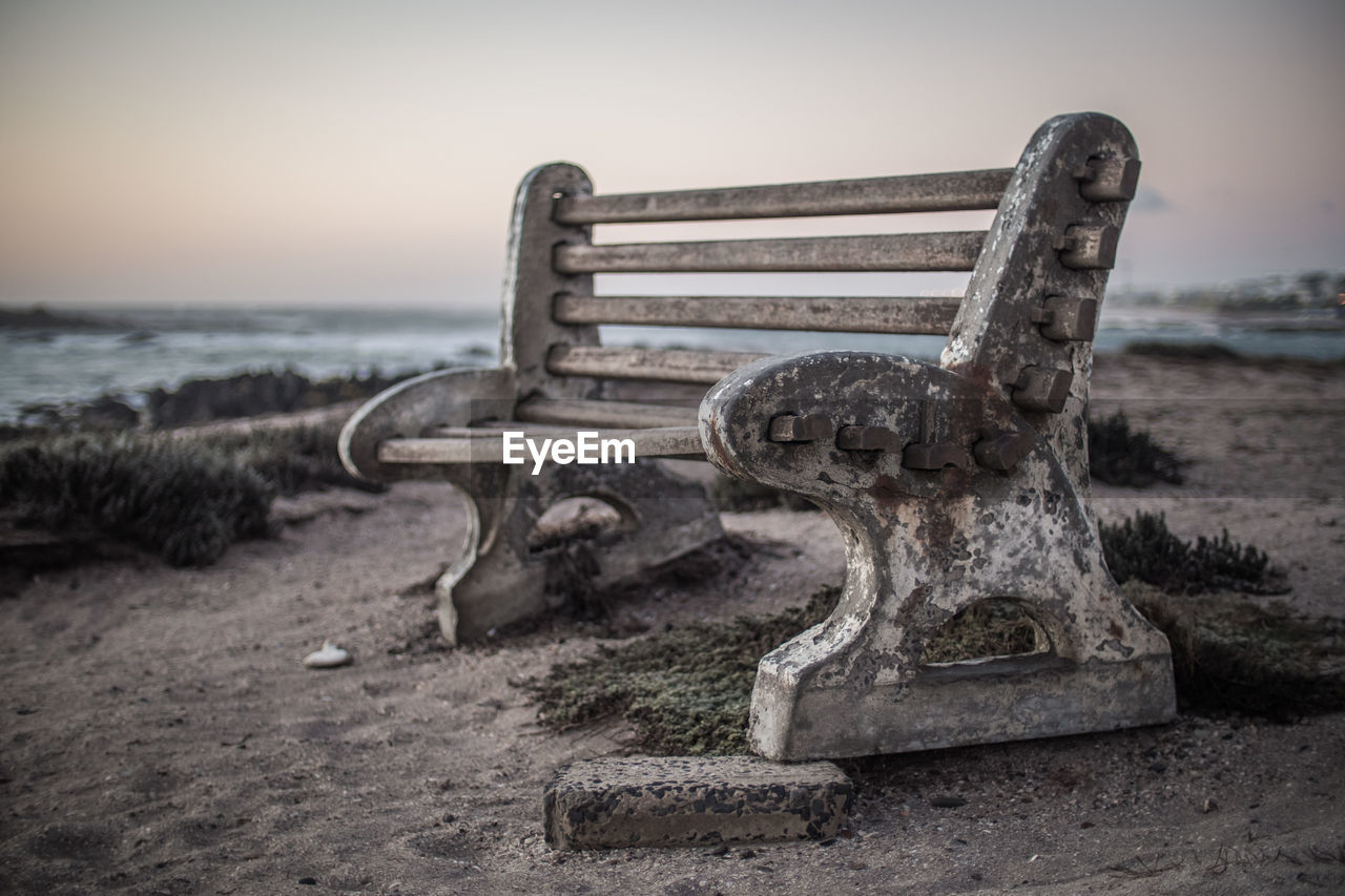 Close-up of old bench at beach