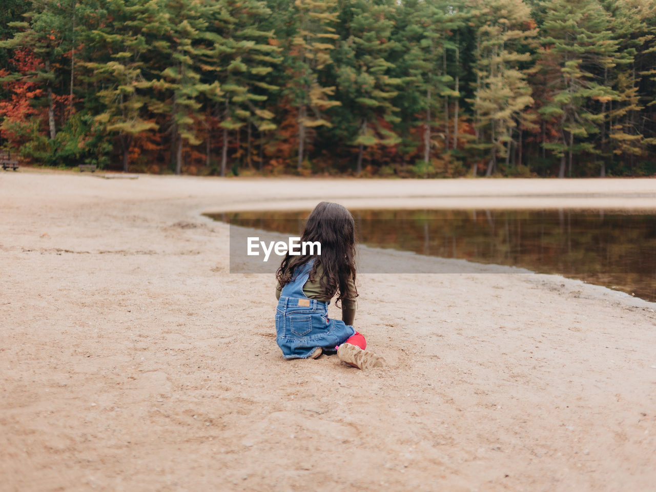 Girl playing by lake on a lovely autumn or fall day