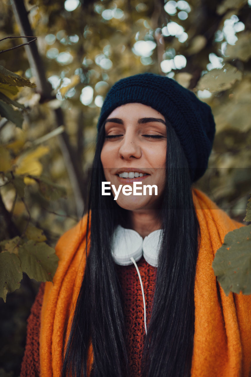 Close-up of woman wearing knit hat standing in forest