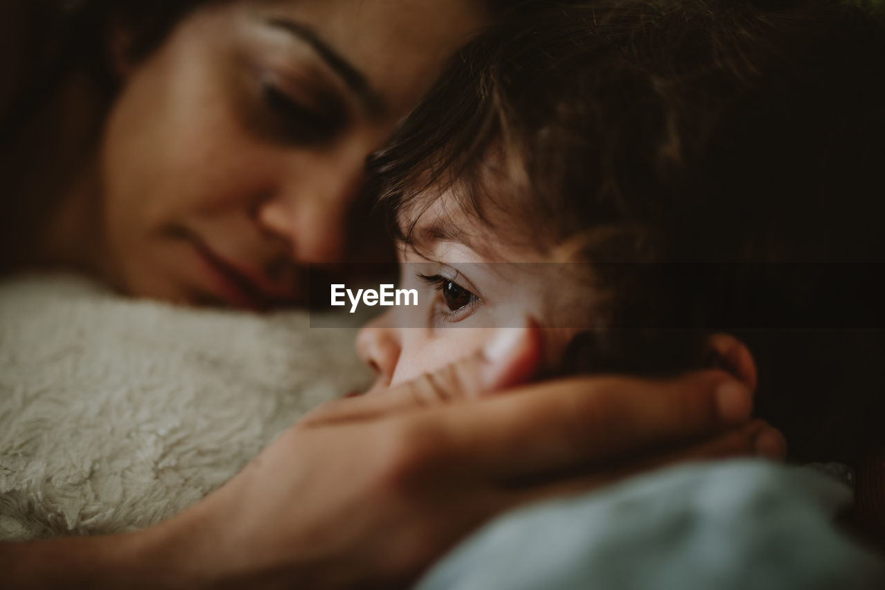 Woman touching daughter on bed