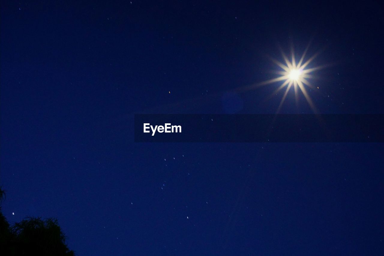 Low angle view of moon against blue sky at night