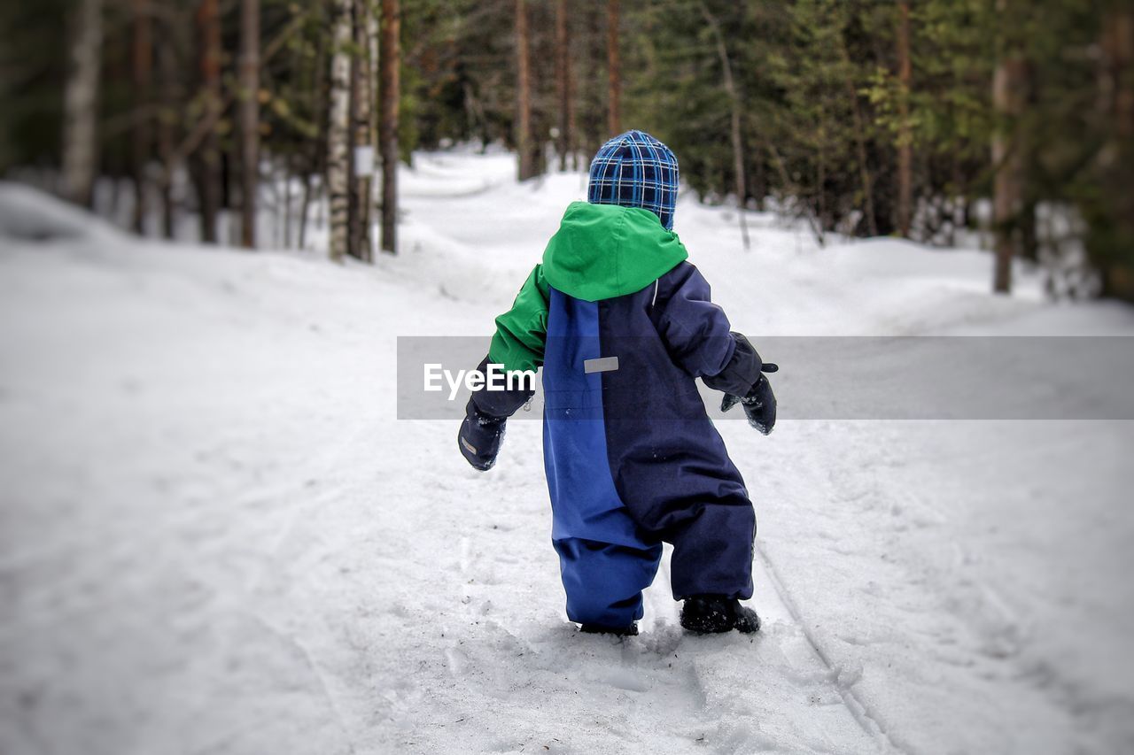 Rear view of boy walking in snow