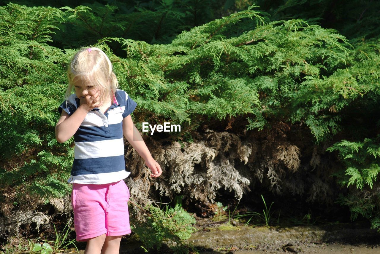 Cute girl standing against plants