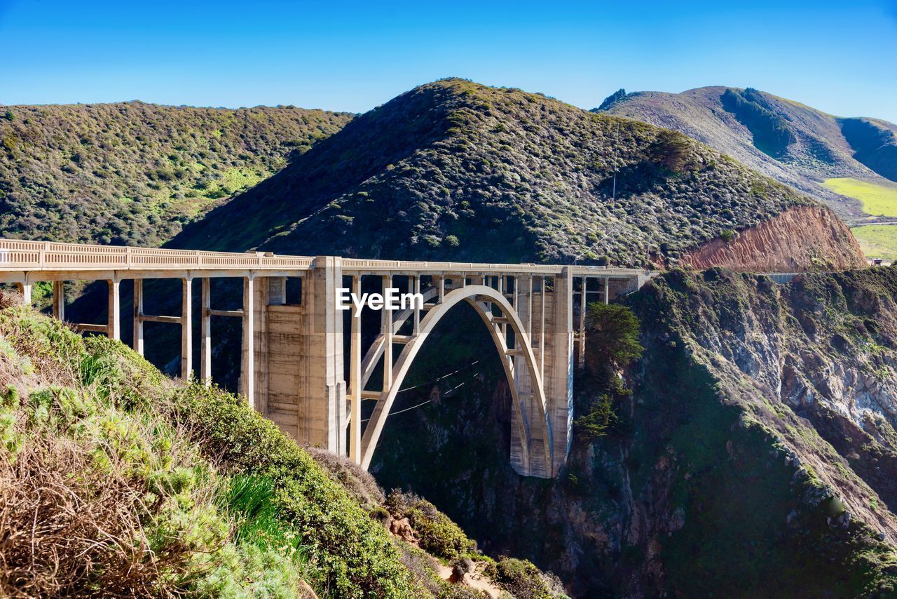 Arch bridge over mountains against sky