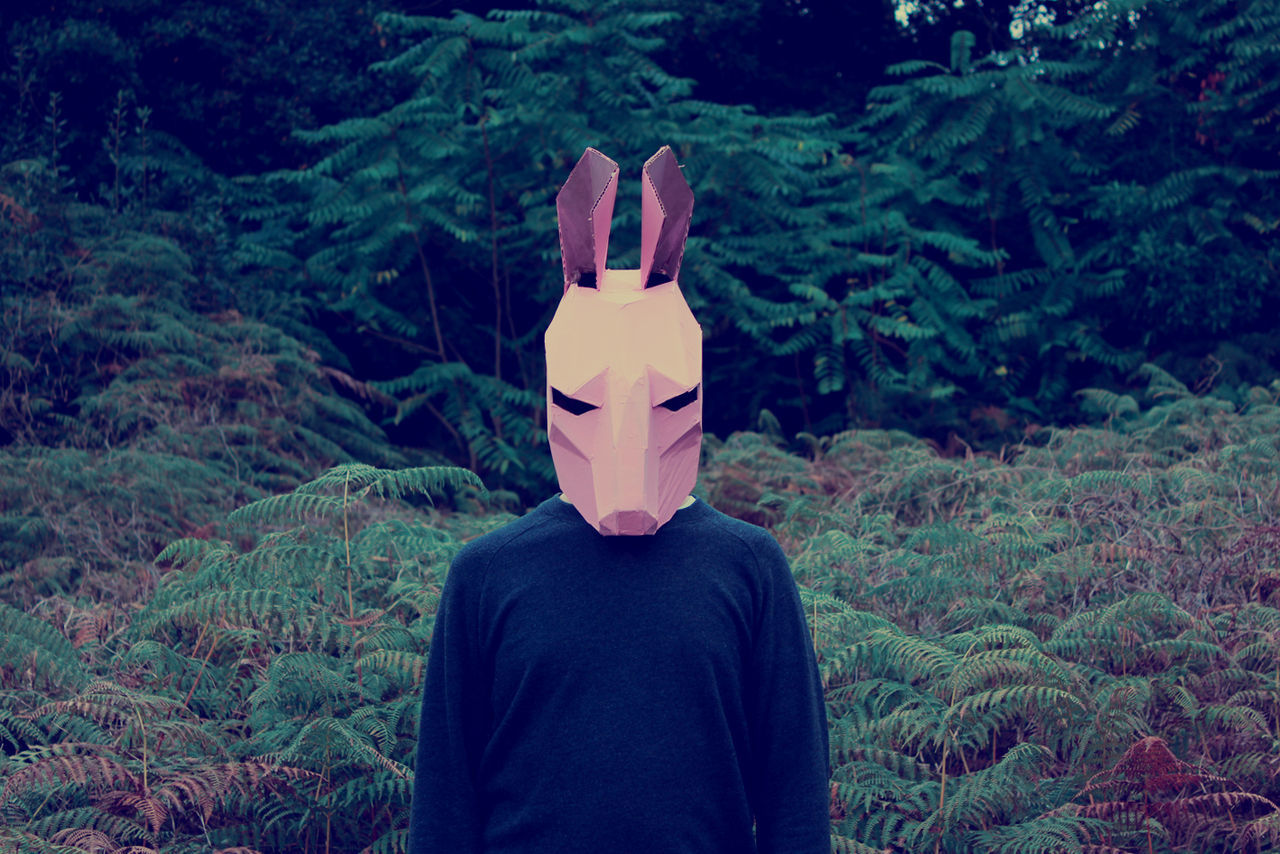 Man wearing mask standing against plants