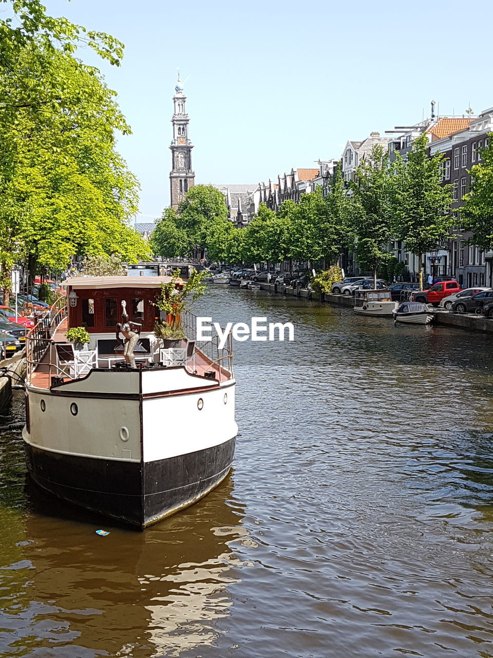 SAILBOATS MOORED ON RIVER BY BUILDINGS IN CITY