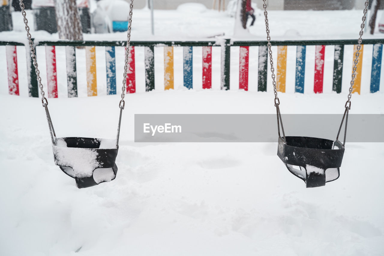 HIGH ANGLE VIEW OF SNOW COVERED SWING IN FIELD