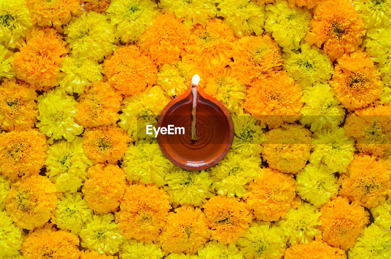 Decorative marigold flower rangoli for diwali festival with clay diya lamp.