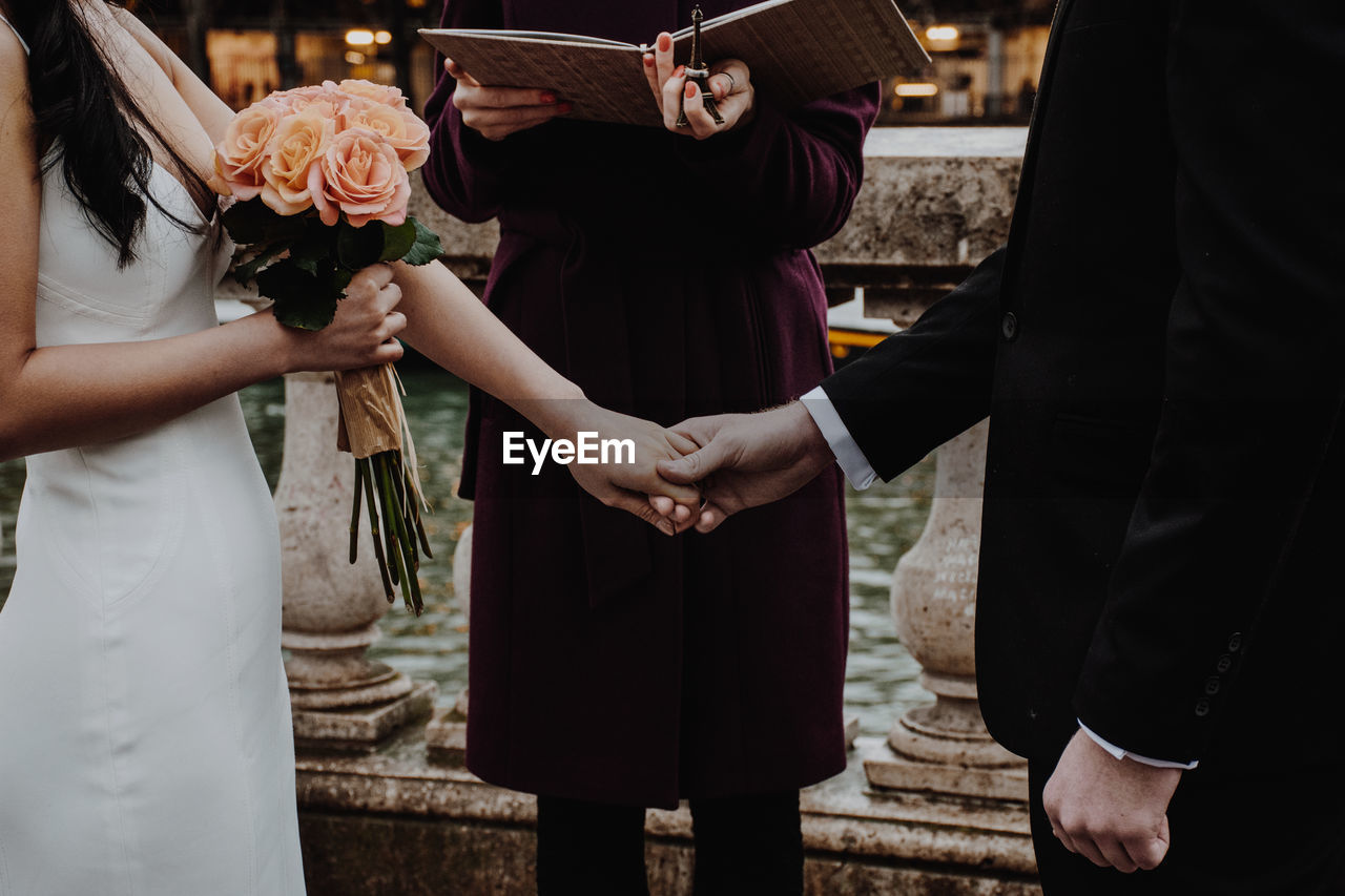 Midsection of couple standing by priest