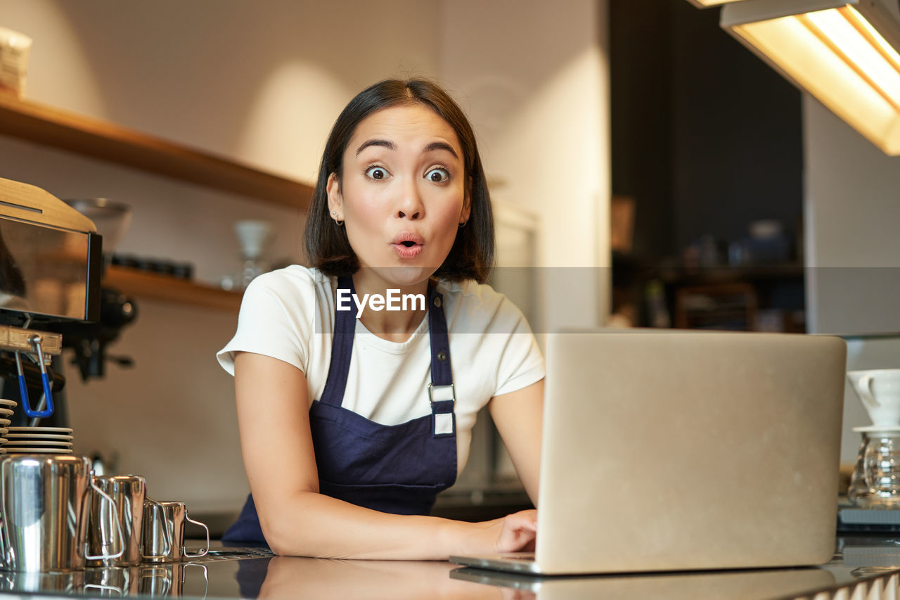 portrait of young woman using laptop while sitting at table