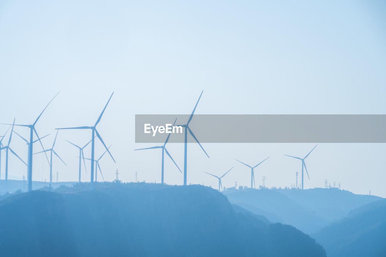 Wind turbines silhouetted on a hilltop