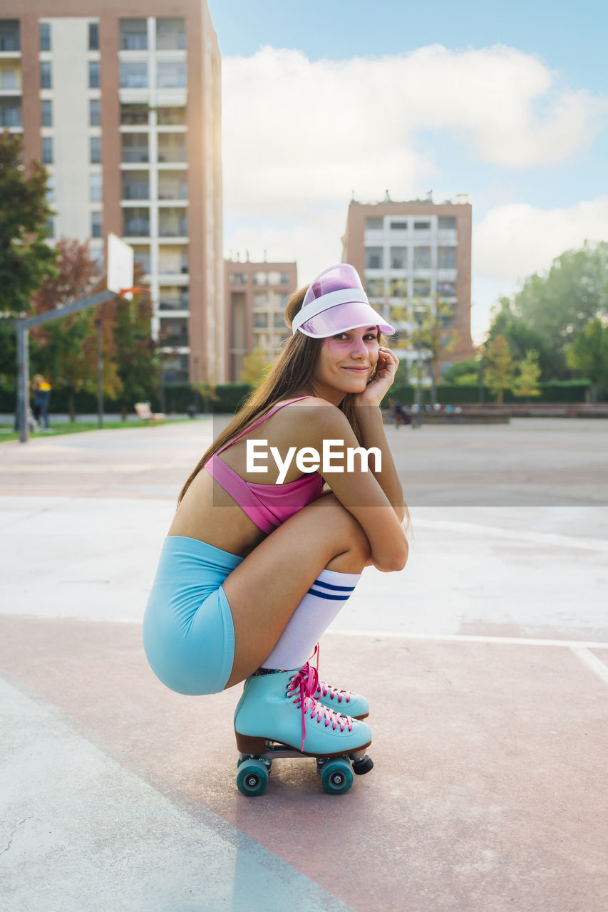 Smiling woman wearing roller skates crouching at sports court