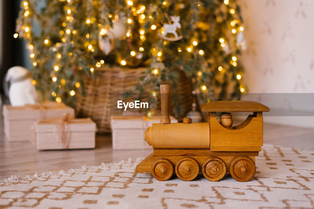 Wooden toy locomotive on the background of a christmas tree in the children's room