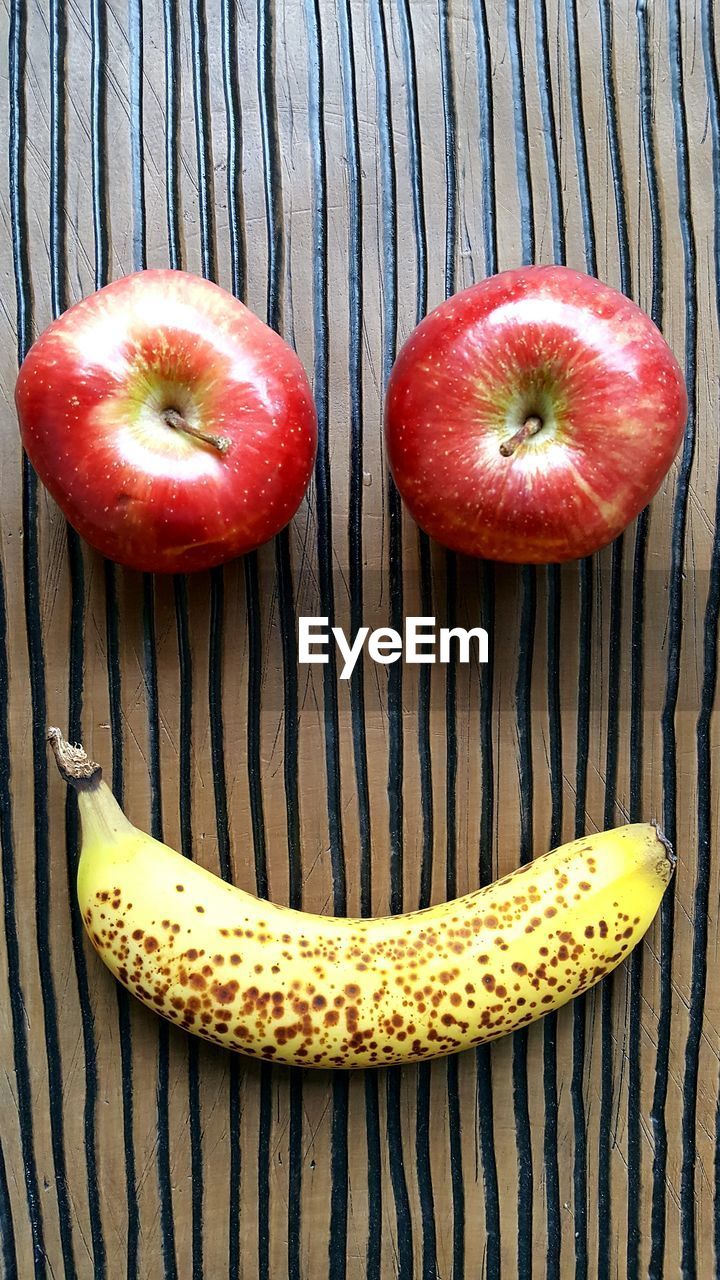High angle view of smiley face made by apples and banana on table