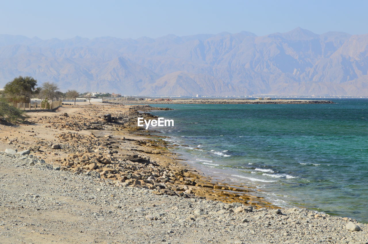 SCENIC VIEW OF SEA AGAINST MOUNTAINS