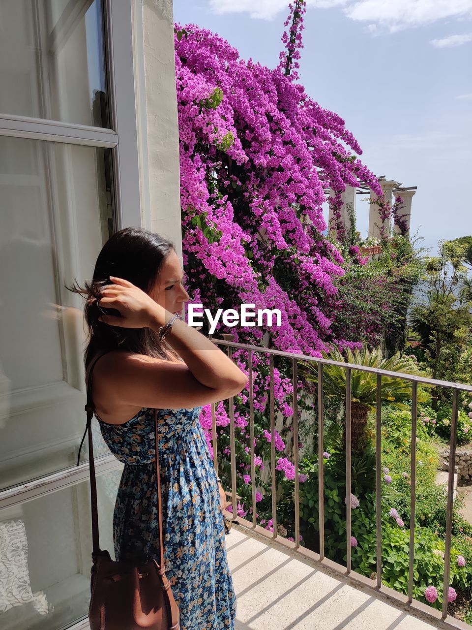 Woman standing by pink flowering plants