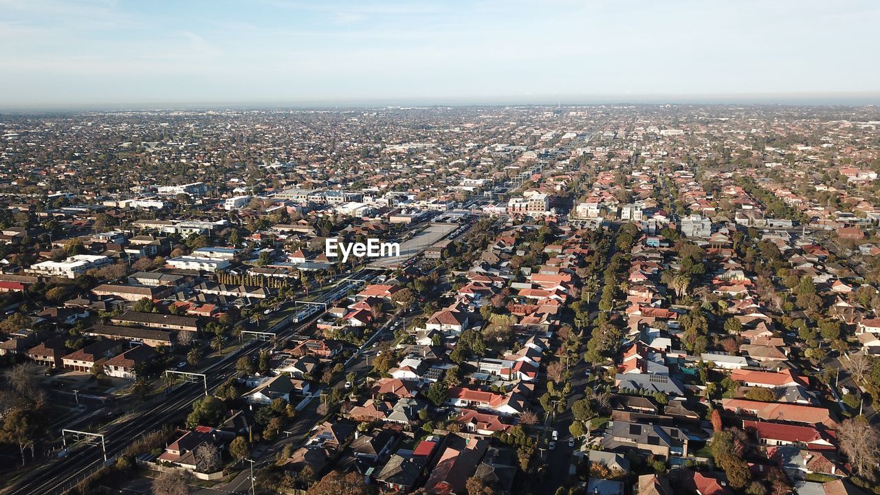 HIGH ANGLE VIEW OF CROWD BY BUILDINGS AGAINST SKY