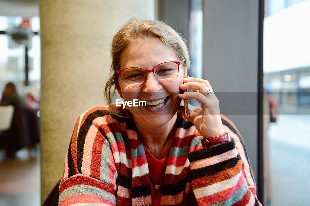 Close-up of cheerful mature woman talking on phone while sitting outdoors