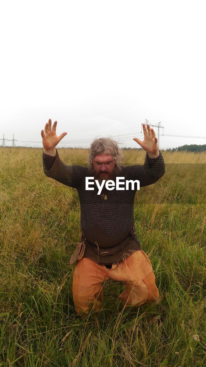 FULL LENGTH OF MAN SITTING IN FIELD