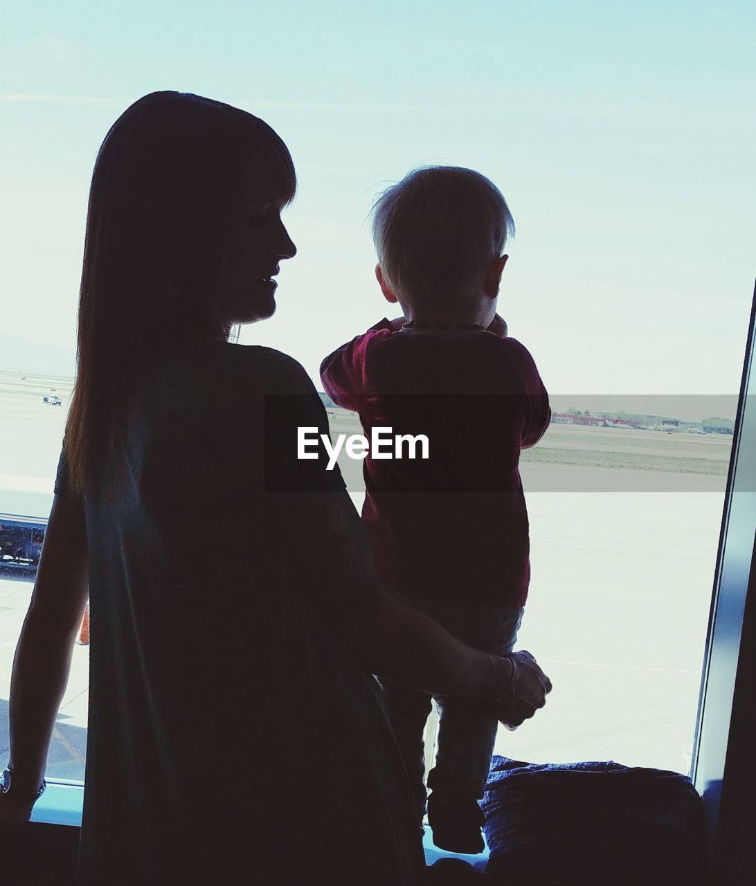 Mother with son standing by window at airport