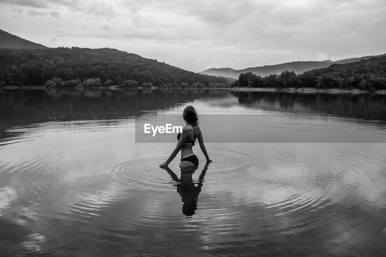 Woman standing in lake against sky