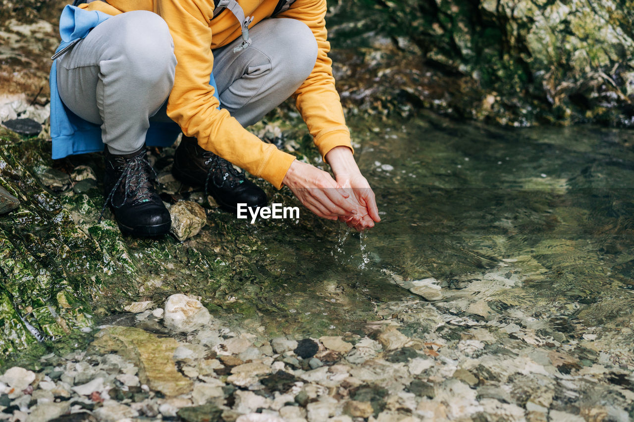 Hiker woman washes her hands in a mountain stream.