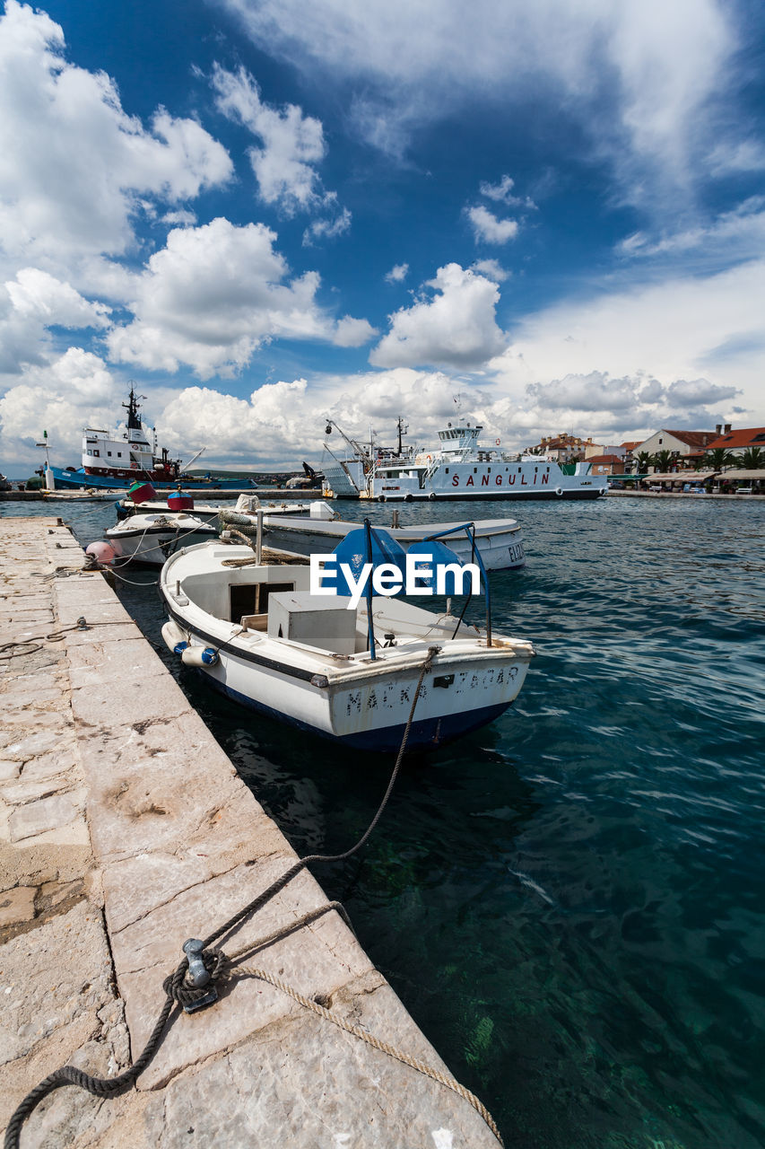 BOAT MOORED AT HARBOR AGAINST SKY