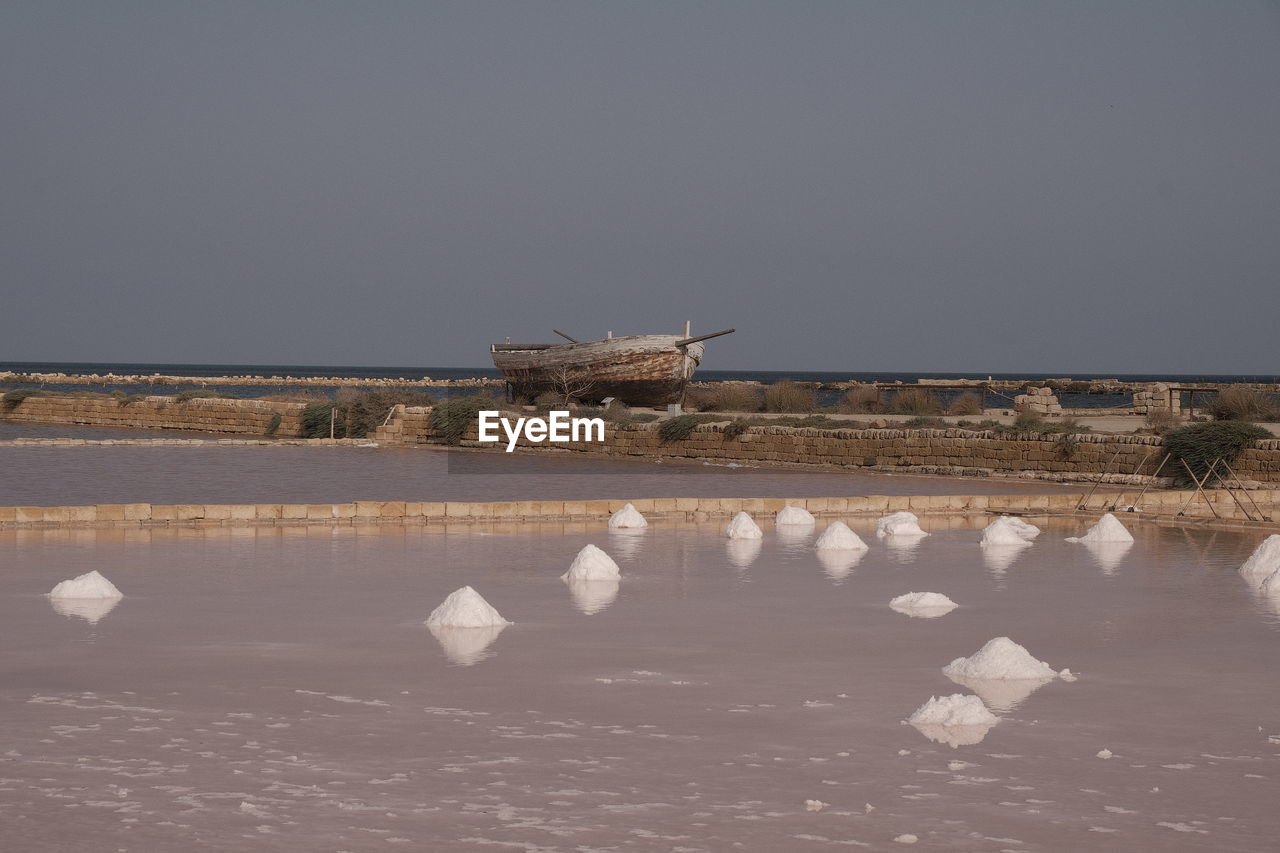 water, reflection, sea, nature, salt evaporation pond, sky, shore, no people, bird, coast, land, ice, animal, environment, salt - mineral, snow, ocean, horizon, day, animal themes, animal wildlife, tranquility, scenics - nature, beauty in nature, outdoors, wave, architecture, beach, salt basin, mineral, tranquil scene, vehicle, cold temperature, wildlife, built structure, landscape, travel destinations, group of animals, salt flat, winter