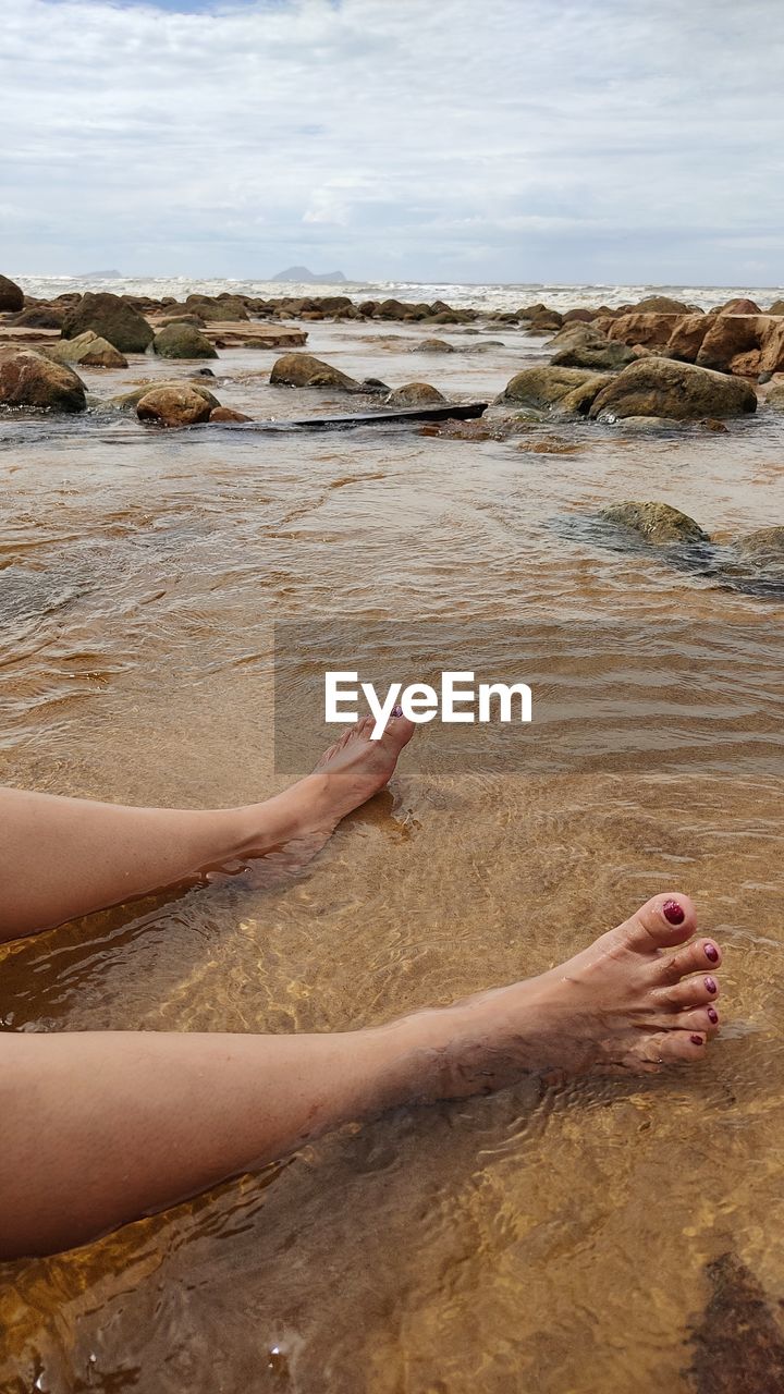 LOW SECTION OF PERSON ON ROCK AT BEACH