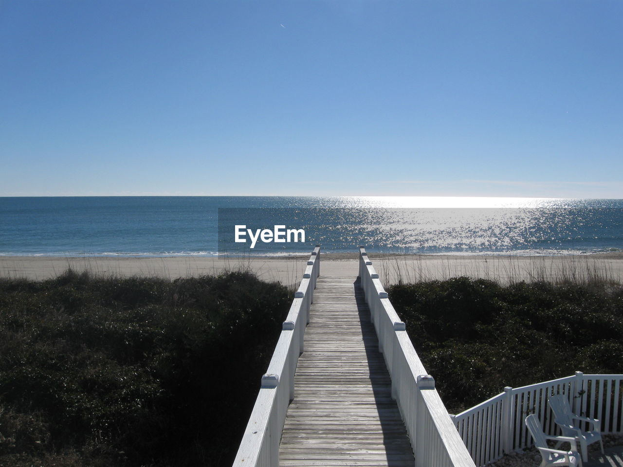 Empty white wooden footpath towards sea