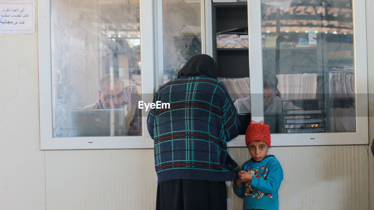 Rear view of people standing in glass window