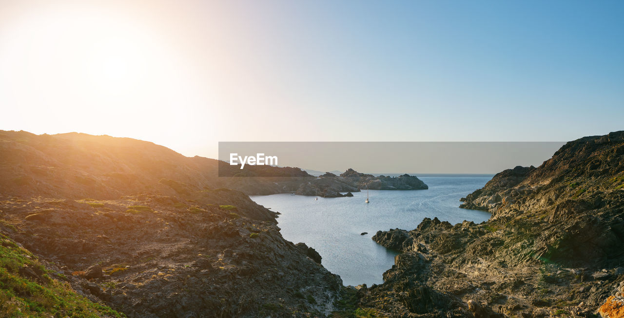Scenic view of sea and mountains against clear sky