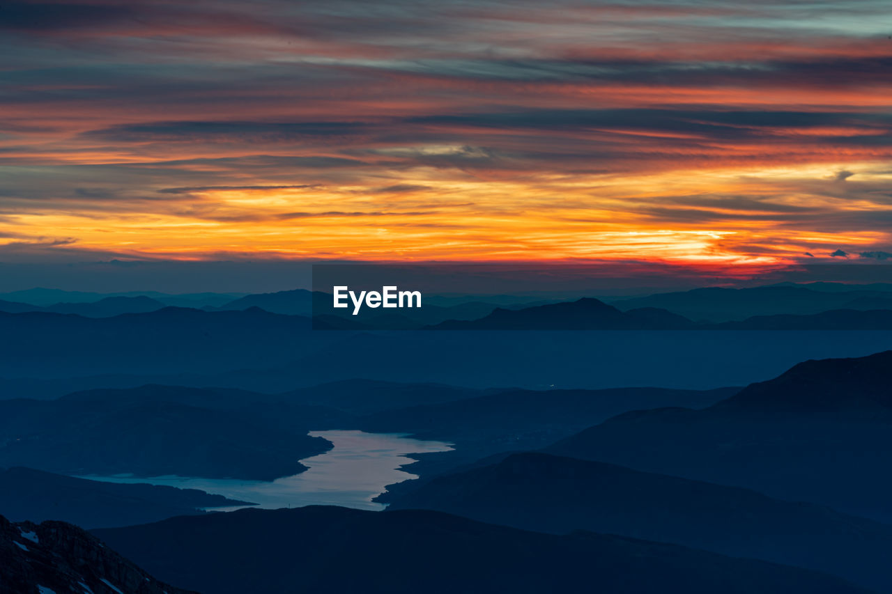 Fiery sky at sunset of the campotosto laka from the top of gran sasso of italy