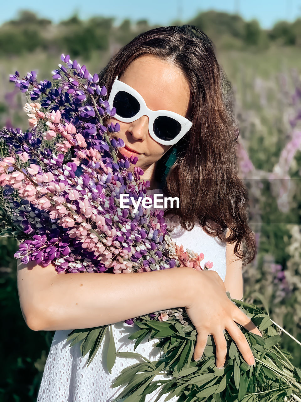 Low angle view of woman wearing sunglasses against pink flowering plants