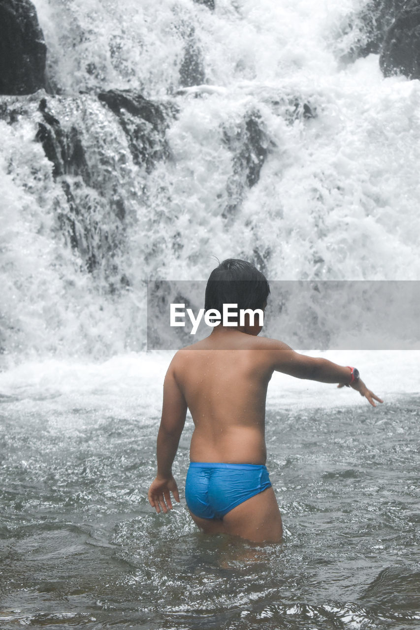 Shirtless boy swimming in pool