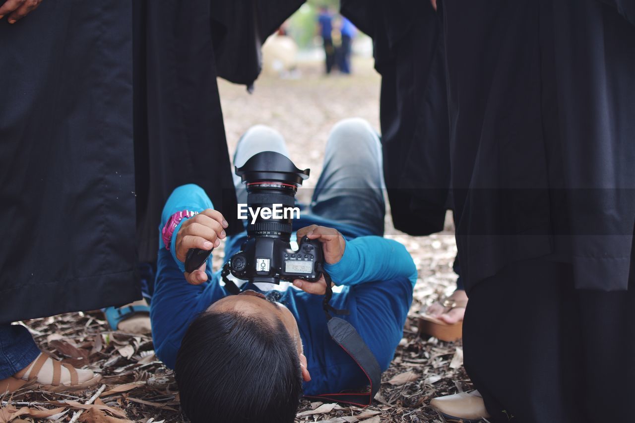 Man lying on ground while photographing through camera