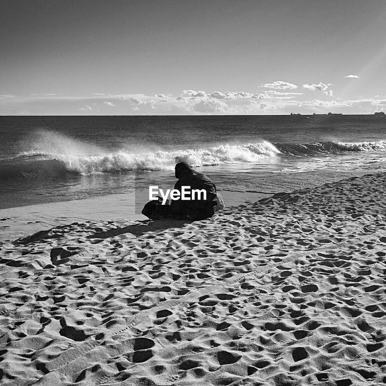 Person sitting on beach against sky