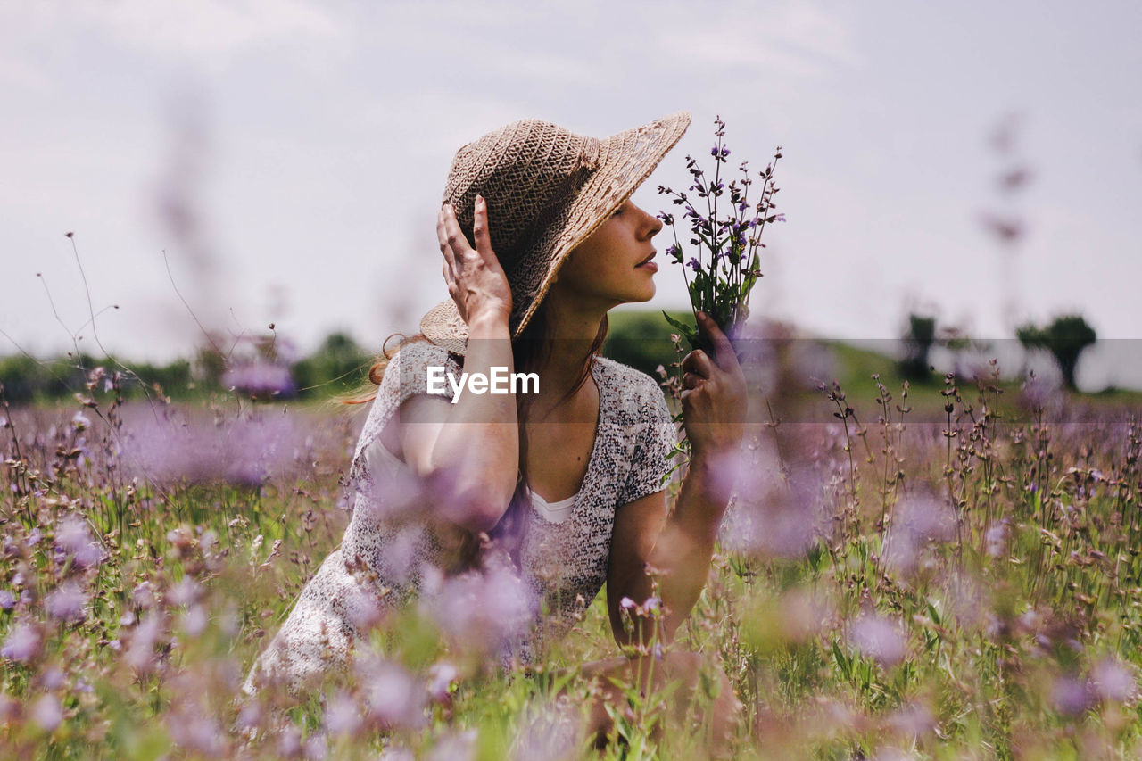 Woman smelling flowers on field