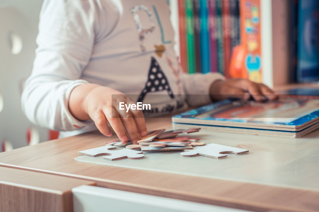 Midsection of woman adjusting jigsaw puzzle on table