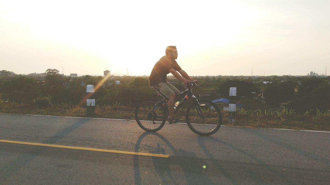 MAN RIDING BICYCLE ON STREET IN CITY