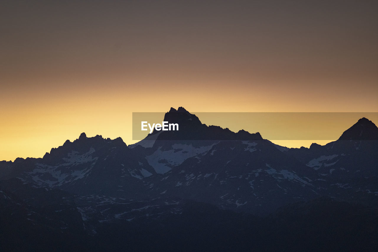 Scenic view of snowcapped mountains against clear sky during sunset