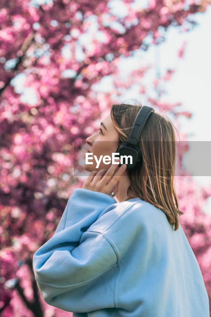 side view of young woman looking away while standing outdoors