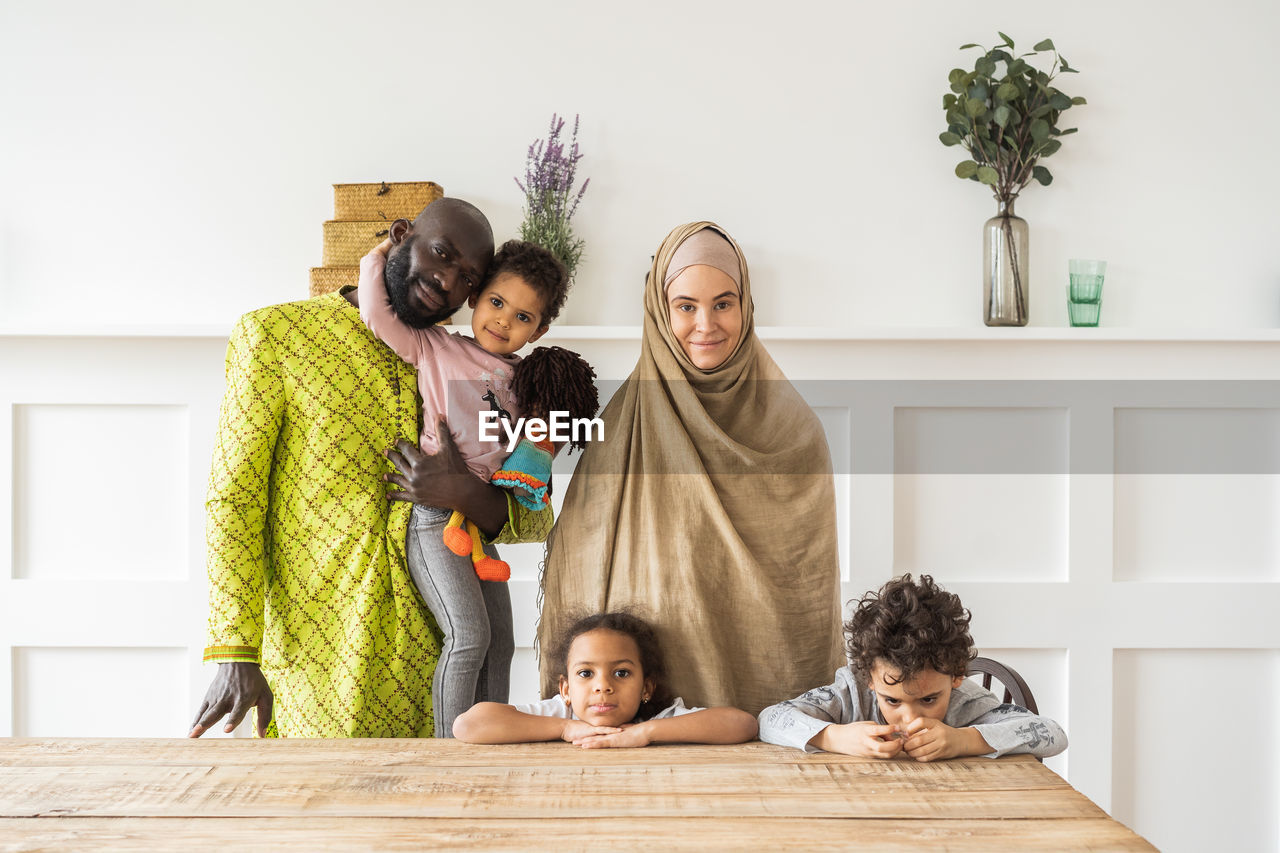 FULL LENGTH OF FATHER AND DAUGHTER STANDING BY TABLE