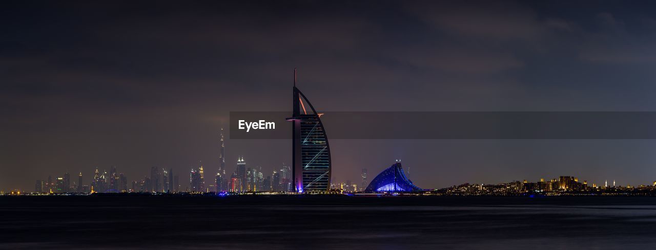 ILLUMINATED MODERN BUILDINGS AGAINST SKY AT NIGHT IN CITY