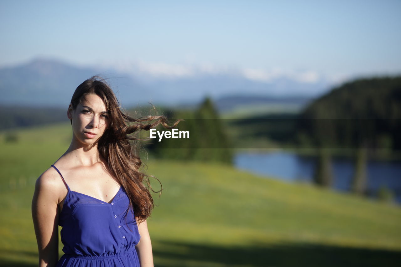 Portrait of beautiful young woman standing on field