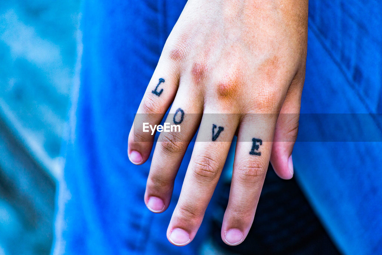 Cropped image of hand with love text tattoo