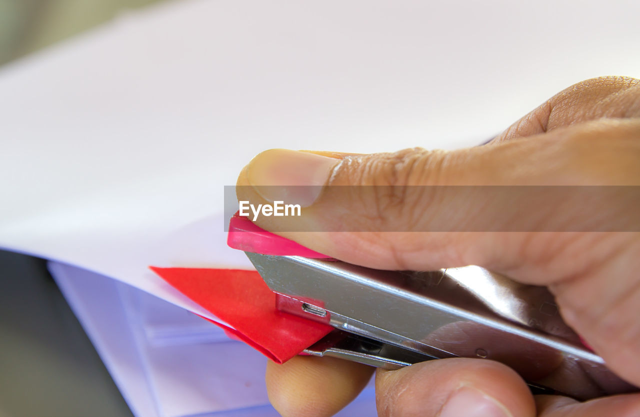 Close-up of cropped hand using stapler