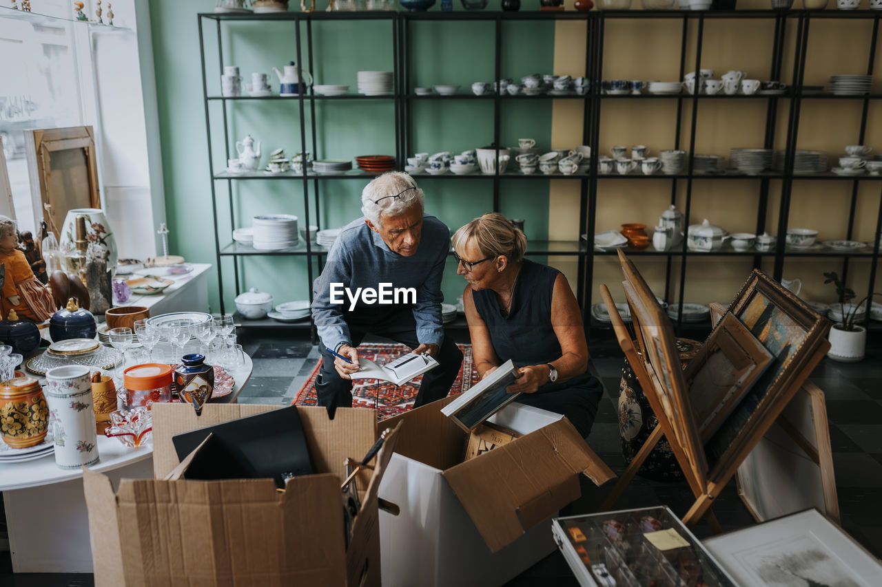 Male and female colleagues discussing while sitting in antique shop