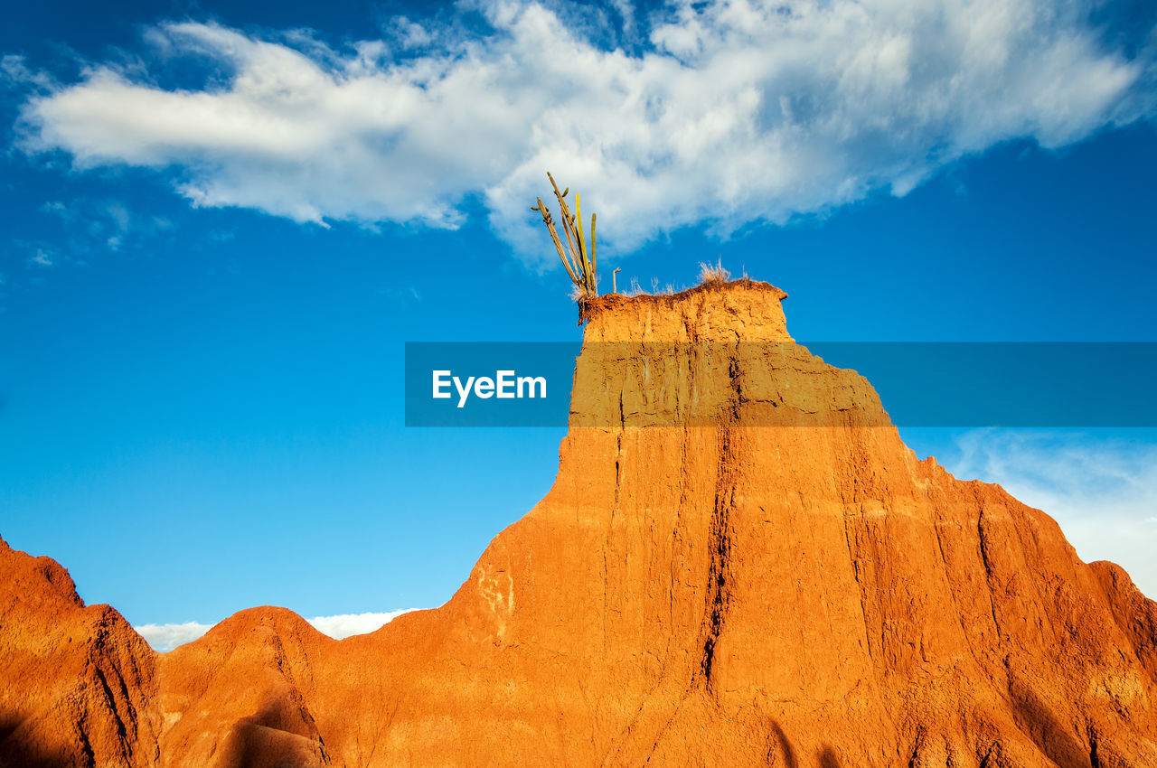 Low angle view of rock formations at tatacoa desert against blue sky